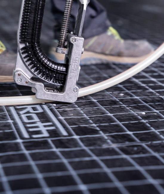 Schläuche einer Fußbodenheizung werden am Grund ausgerichtet